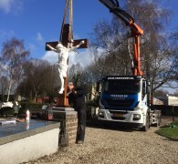 Terugplaatsing van gerestaureerd houten kruis met christus beeld 